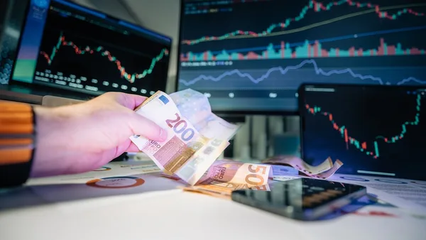 A person holding money in front of a computer screen