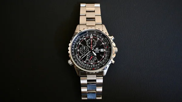 a watch sitting on top of a metal bracelet