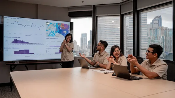 Team collaborates during a business presentation with data on screen.