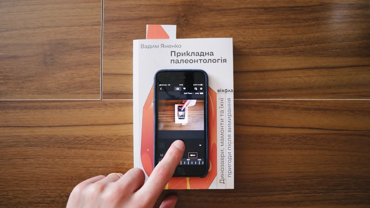a person holding a smart phone on top of a wooden table