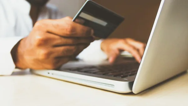 person using laptop computer holding card