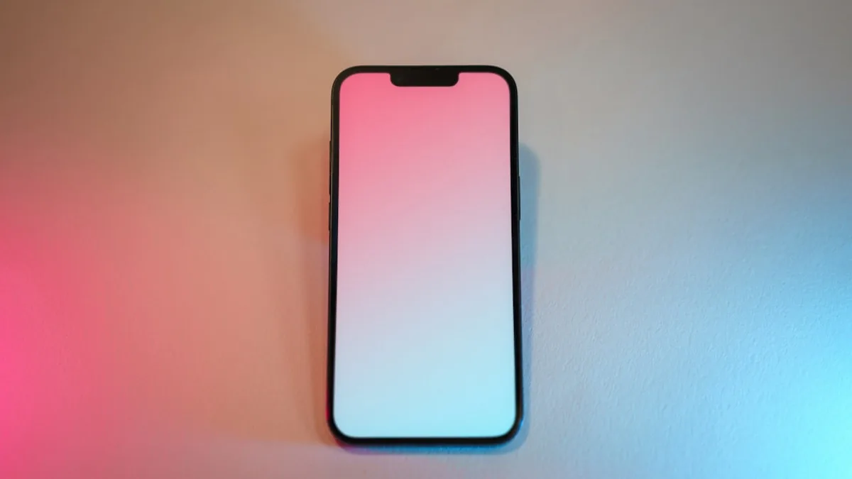 A pink and white cell phone sitting on top of a table