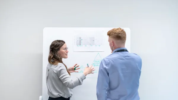 two colleagues discussing ideas at whiteboard