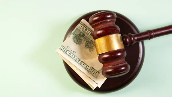 A gavel rests on a sound block with money.