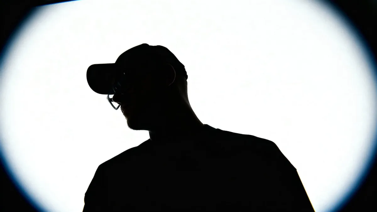 Silhouette of a person wearing a baseball cap and glasses.