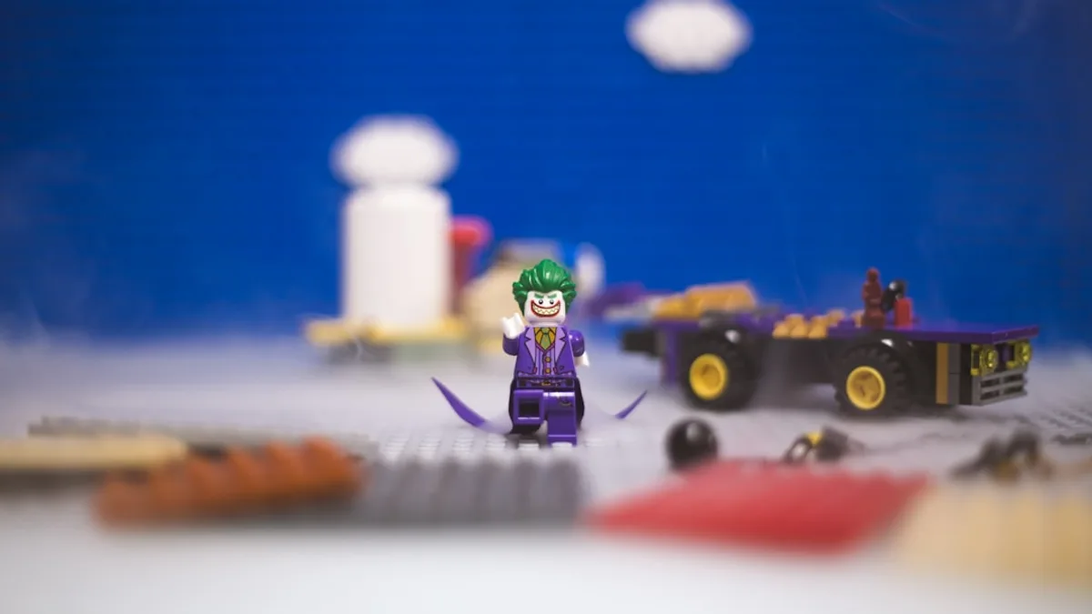 A lego figure standing in front of a toy truck