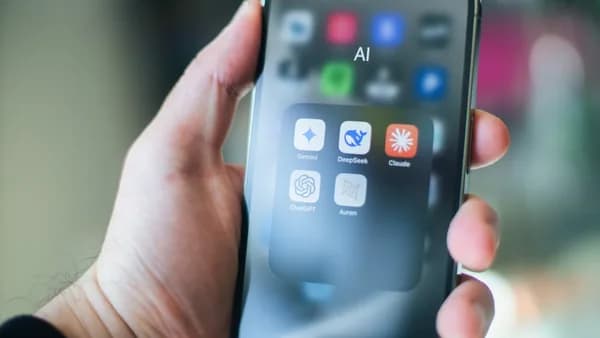 A hand holds a smartphone with various apps.