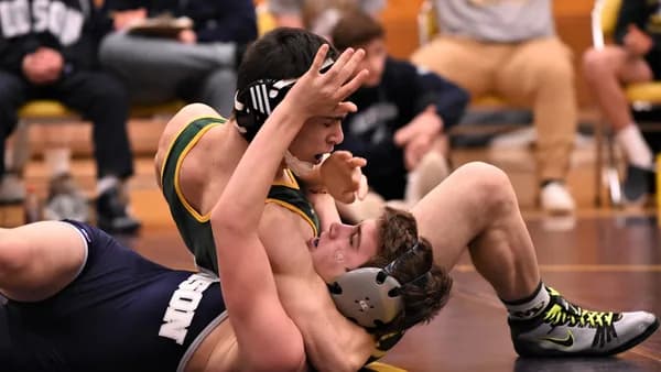 man lying on ground over man wearing green jersey shirt
