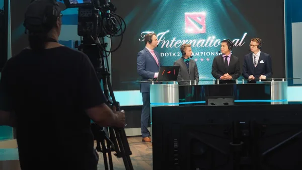 Three men in suits being filmed for dota 2 competition.