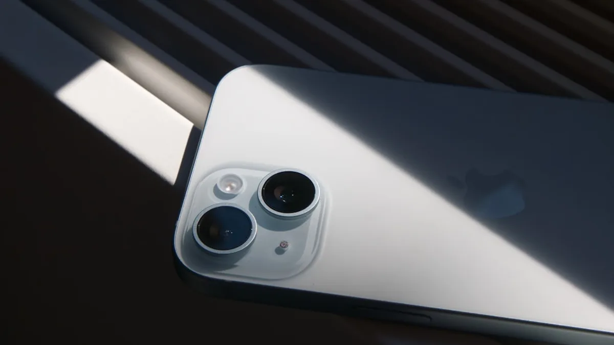 An iPhone rests under sunlight, its camera visible.