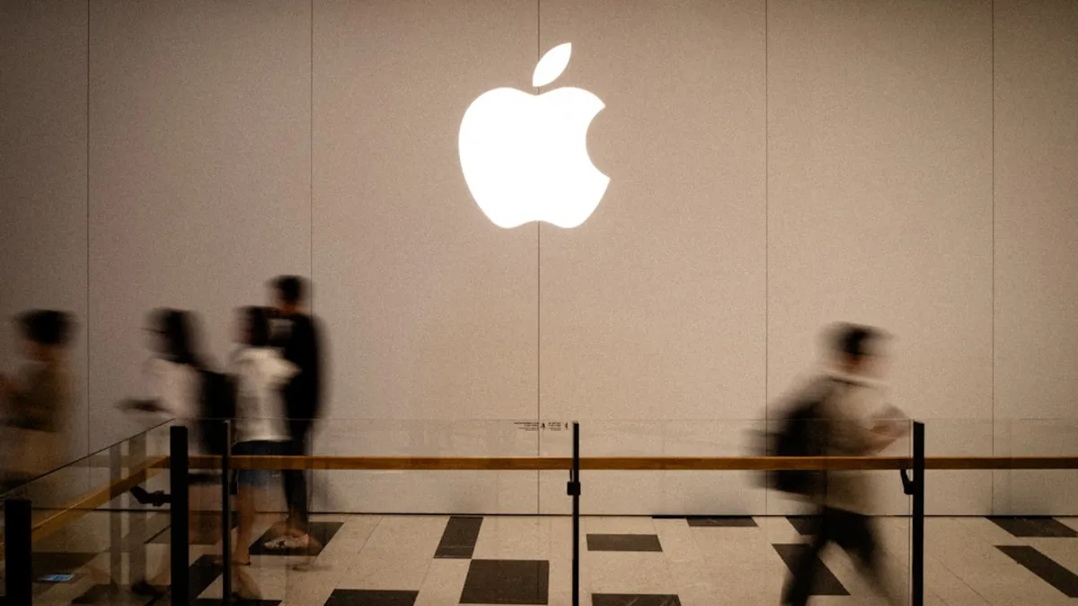 People walk past a large glowing apple logo.