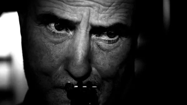 A man plays the harmonica in black and white.