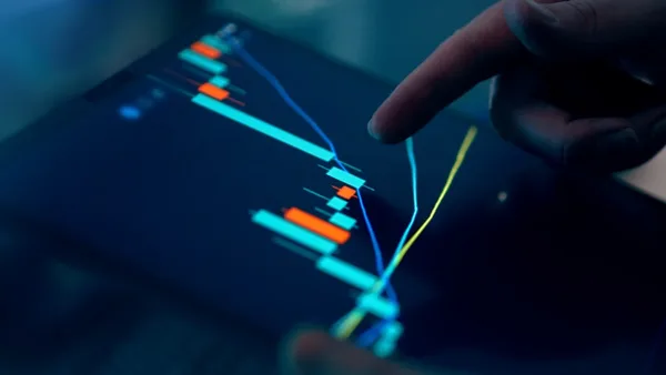 Fingers interacting with a stock market graph on a tablet.