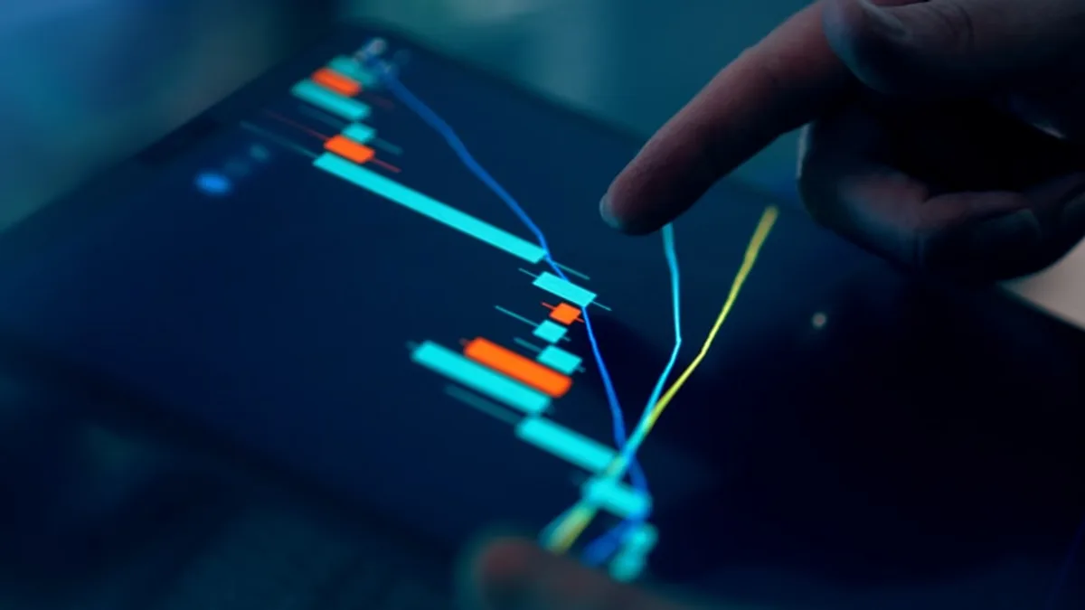 Fingers interacting with a stock market graph on a tablet.
