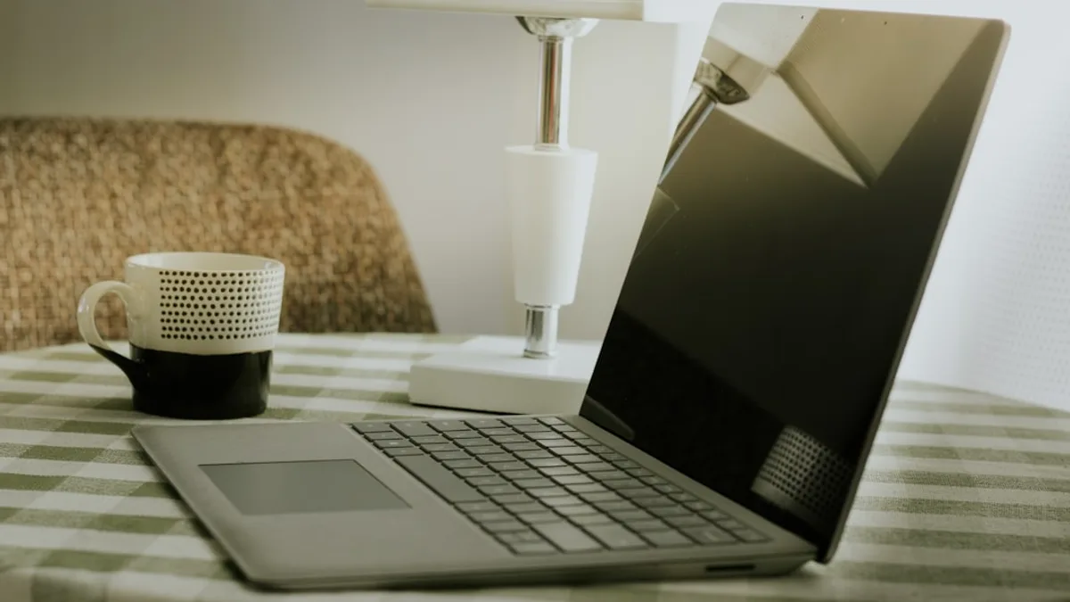 Laptop and coffee cup on a checkered tablecloth.
