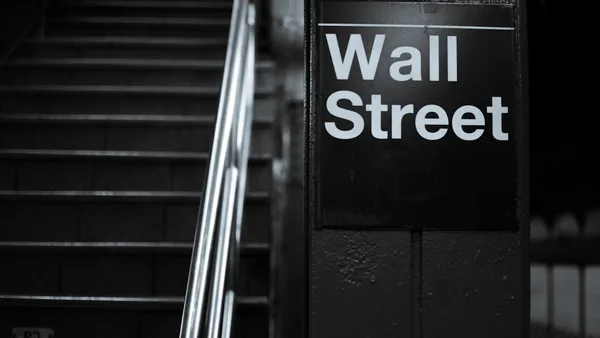 a black and white photo of a wall street sign