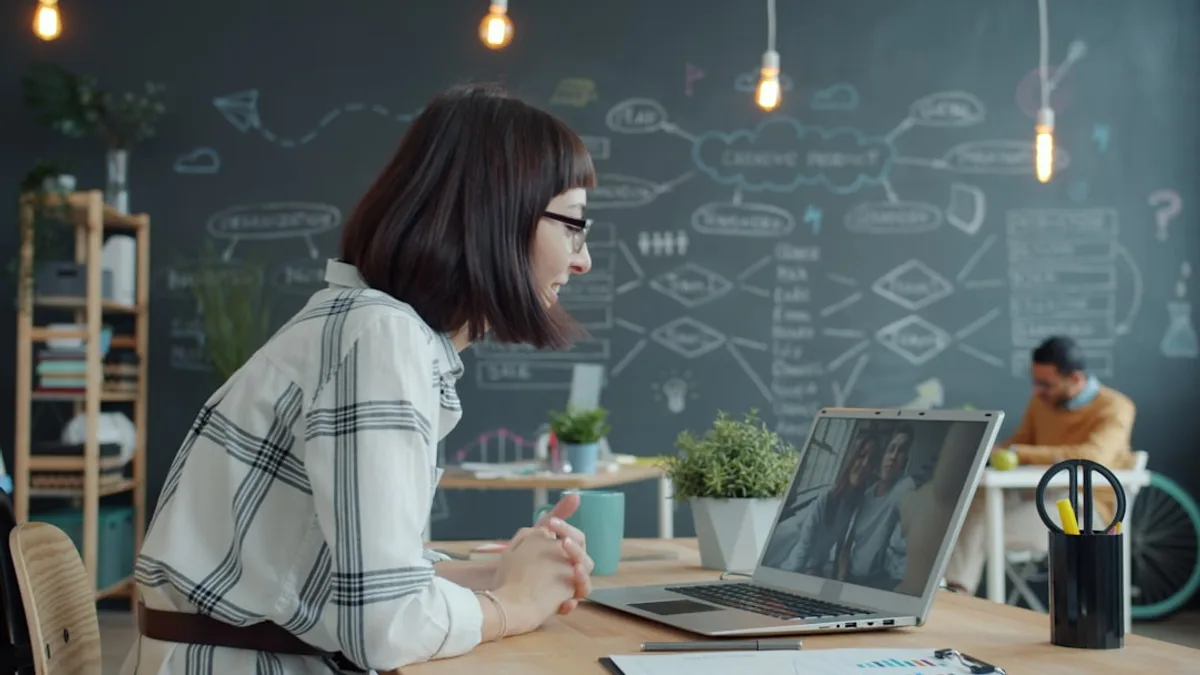 Woman video conferencing with colleagues in a modern office.