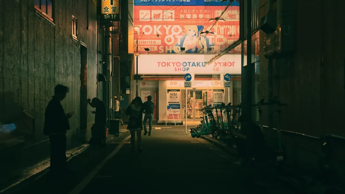 People walking down a dark alley with bright signs.