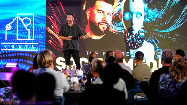 Man presents on stage with robot graphic background