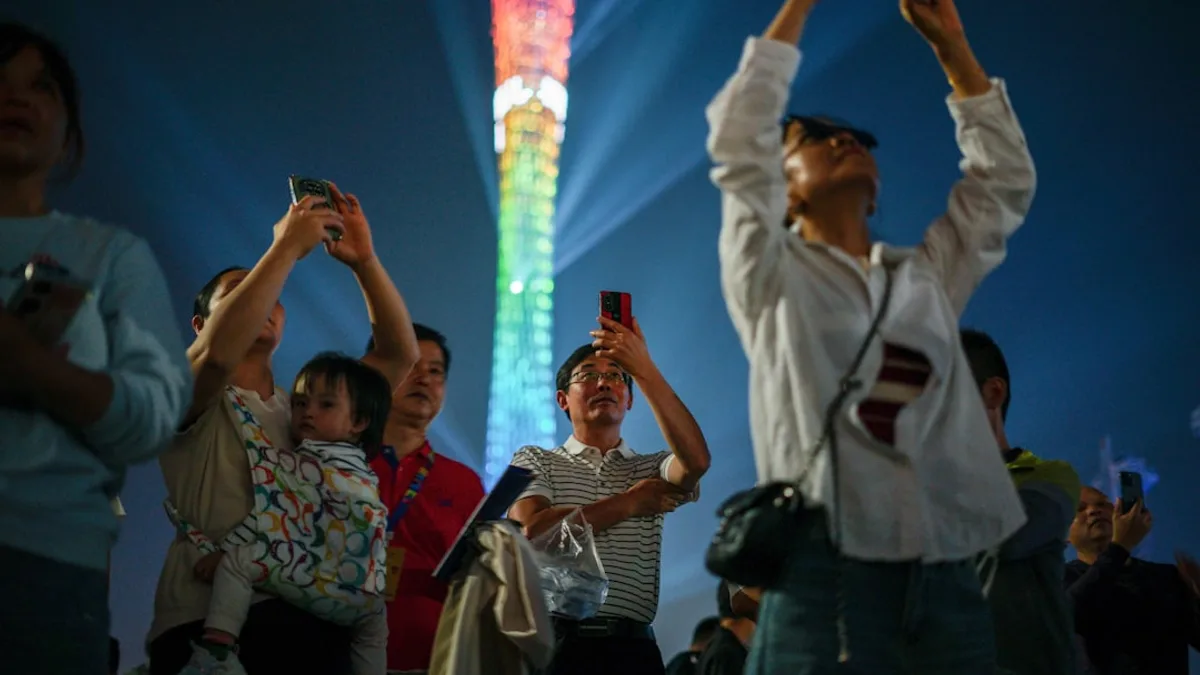 People watching a colorful tower light show at night.
