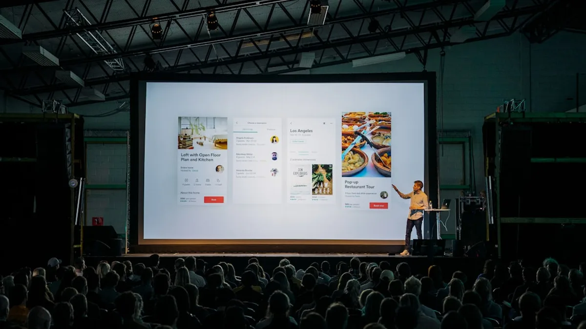 person discussing while standing in front of a large screen in front of people inside dim-lighted room