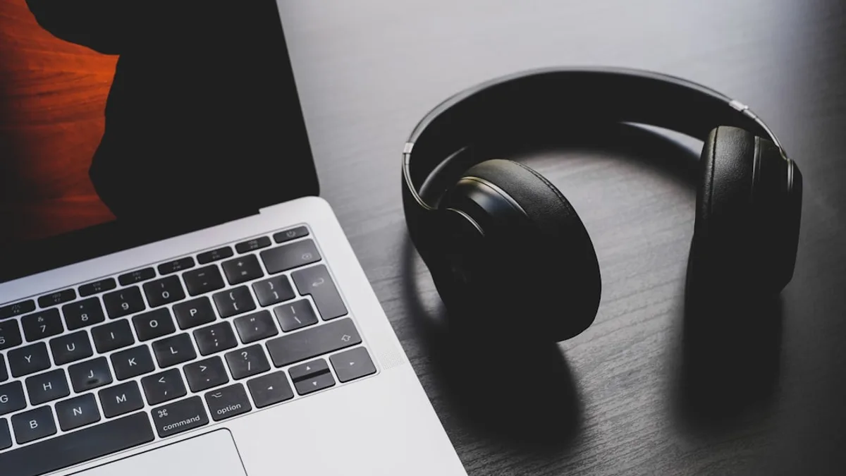 black wireless headphones beside MacBook Pro