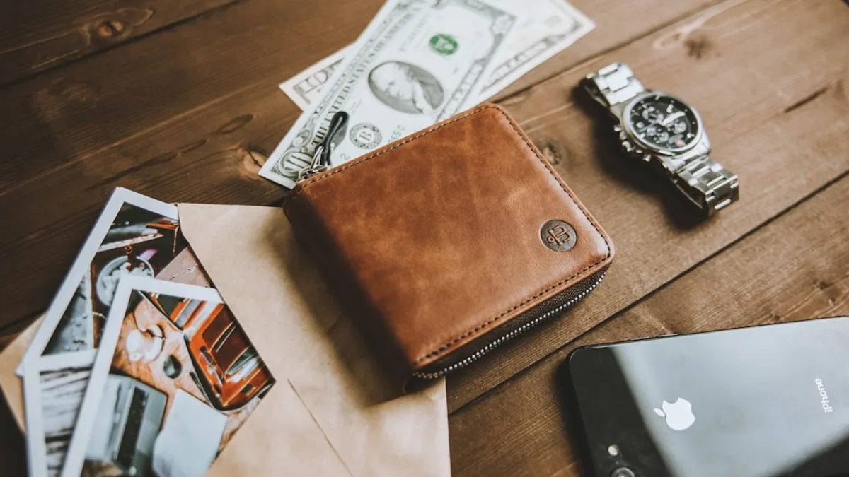 a wallet sitting on top of a wooden table next to a cell phone