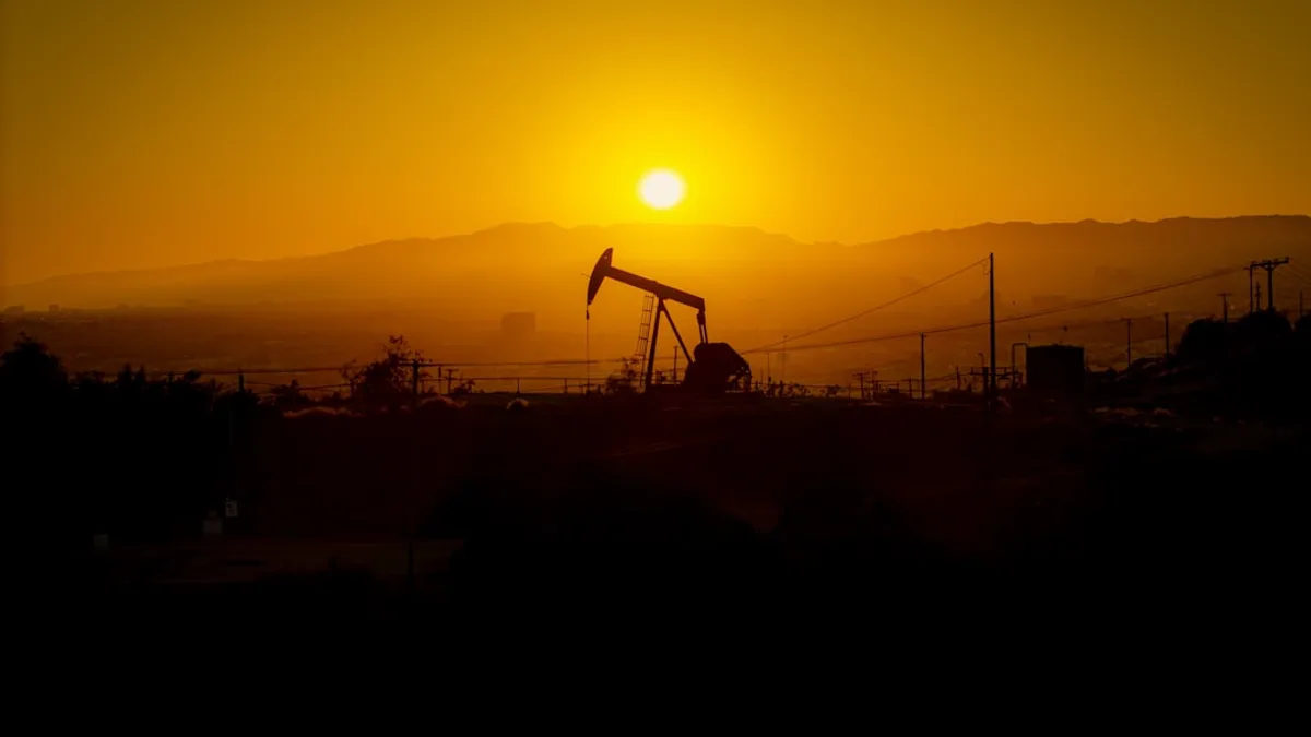 Oil pump jack silhouetted against a hazy sunset