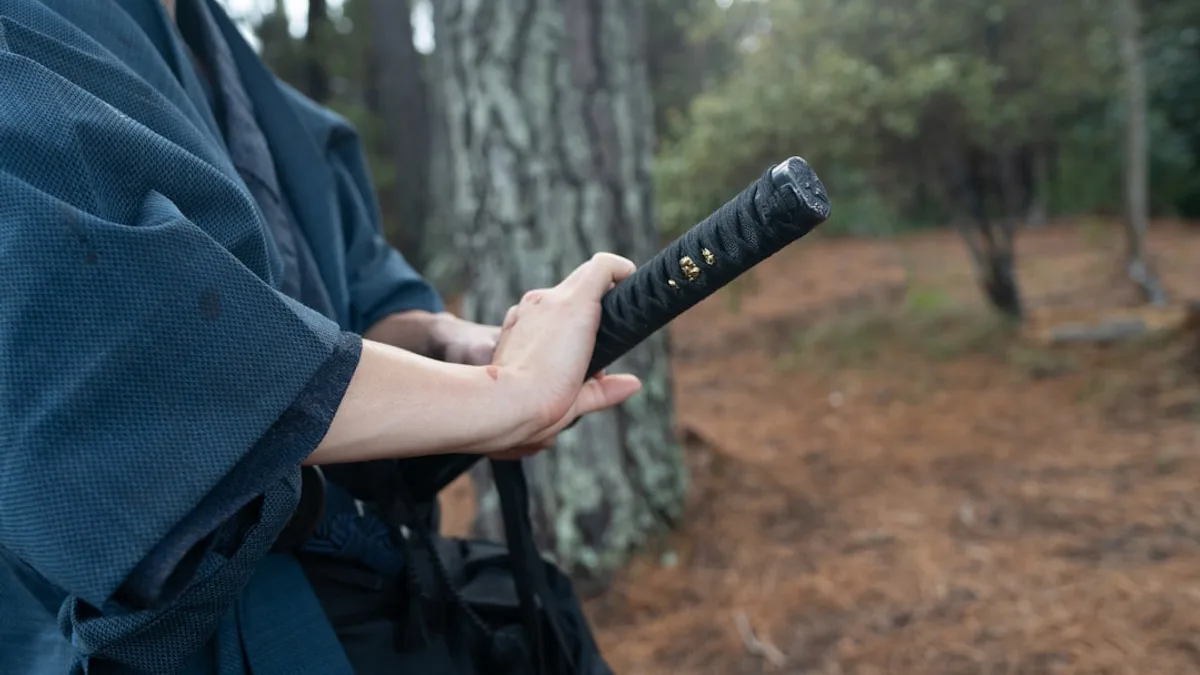 Hands holding a traditional japanese katana sword outdoors.