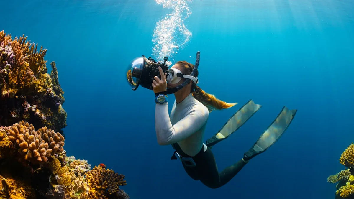 a woman scubas in the ocean with a camera