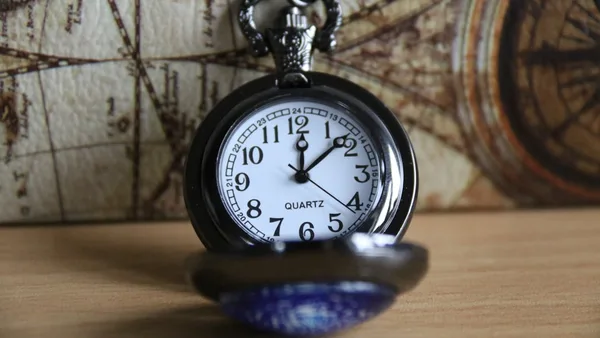 a pocket watch sitting on top of a wooden table