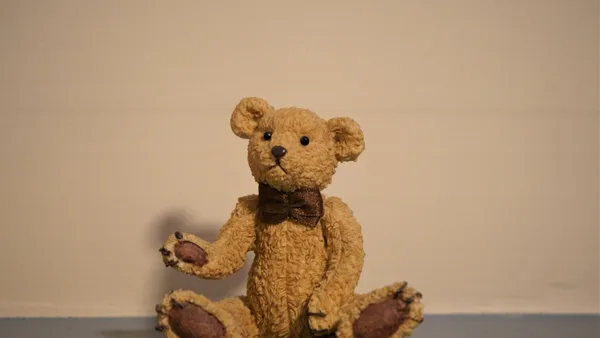 a brown teddy bear sitting on the floor