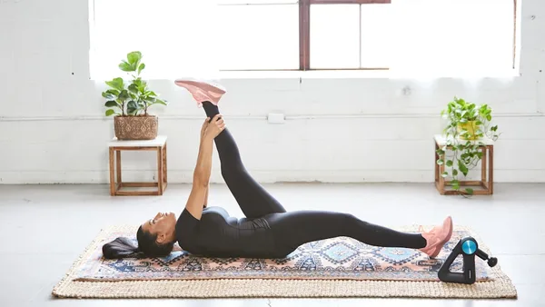 woman in black tank top and black leggings lying on black and white floral area rug