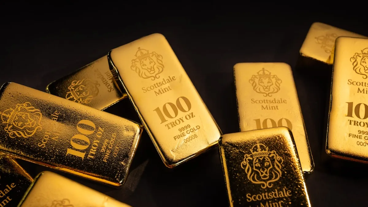 Several gold bars scattered on a dark surface.