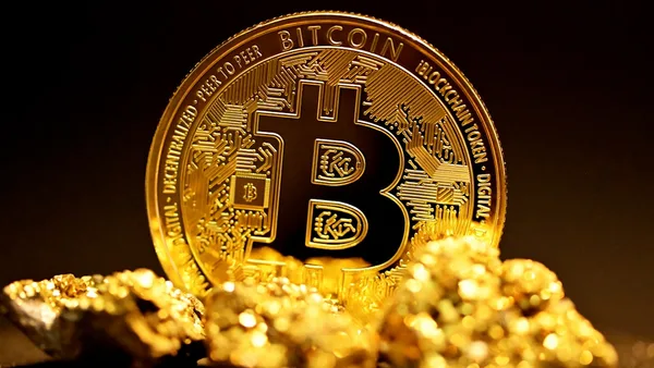a bitcoin sitting on top of a pile of gold nuggets
