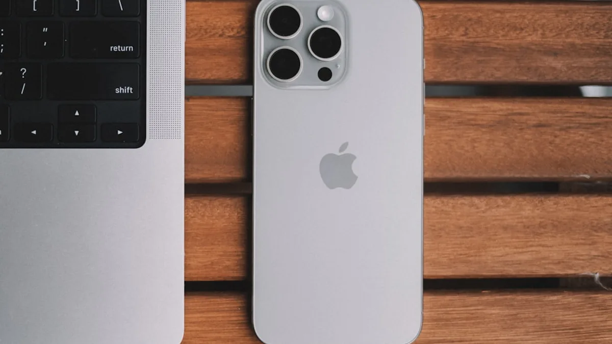 An iPhone and a laptop on a wooden table