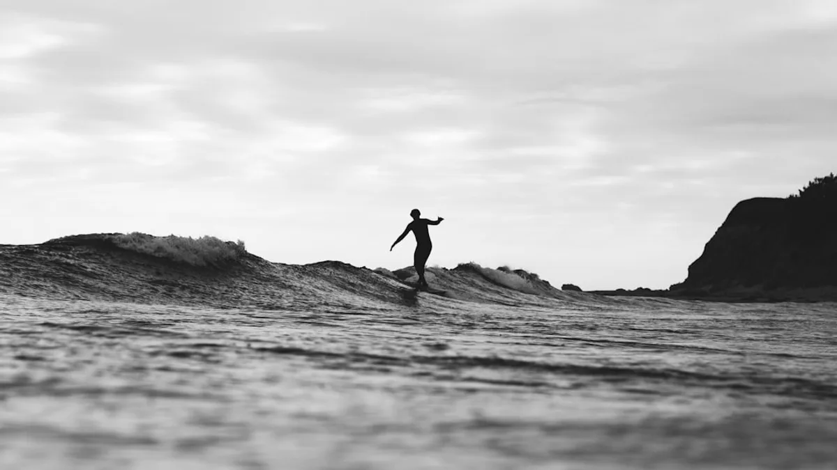 grayscale photography of person surfing on sea