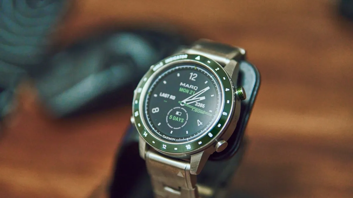 A silver smartwatch with a green bezel on display.