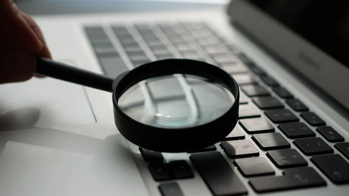magnifying glass near gray laptop computer