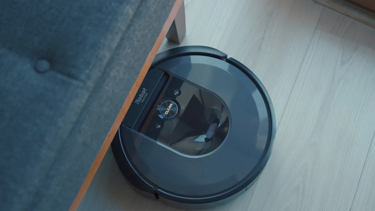 a robotic vacuum is on the floor next to a couch