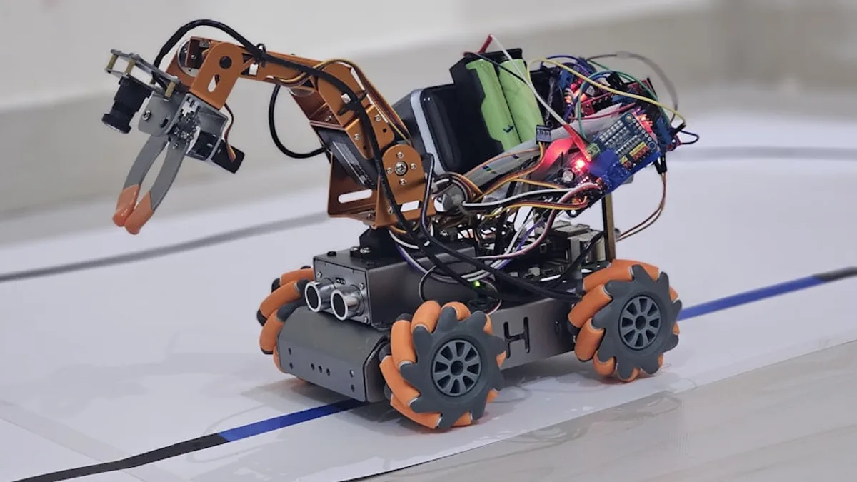 Complex robot with orange wheels and a robotic arm.