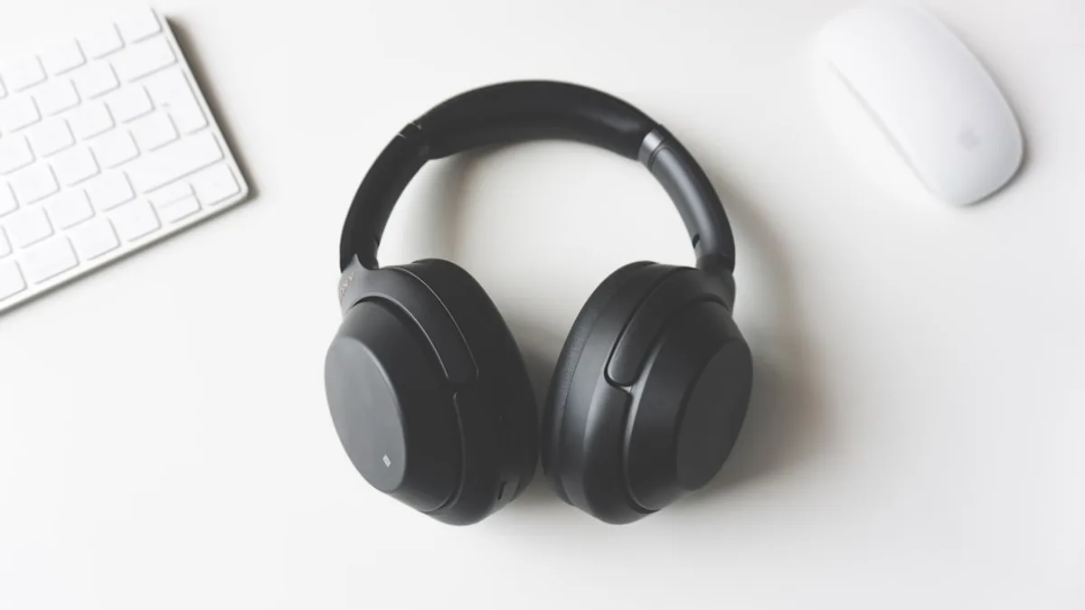 black wireless headphones between Apple Keyboard and Apple Magic Mouse on white surface