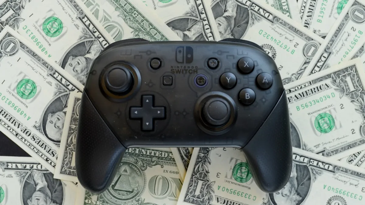 a video game controller sitting on top of a pile of money