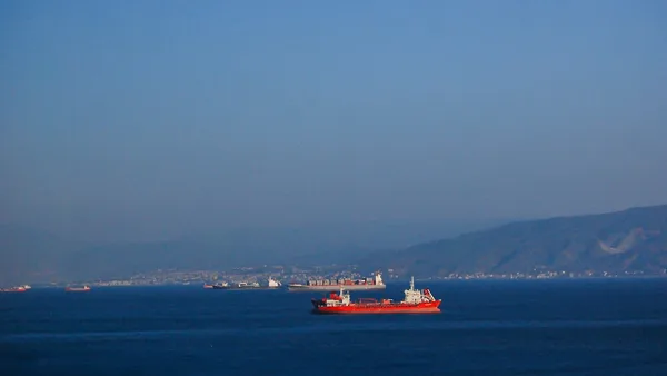 A large red boat floating on top of a large body of water
